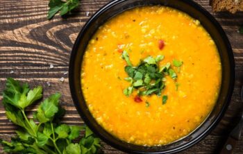 Schüssel mit Möhrensuppe mit Linsen dektoriert mit Koriander