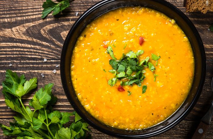 Schüssel mit Möhrensuppe mit Linsen dektoriert mit Koriander